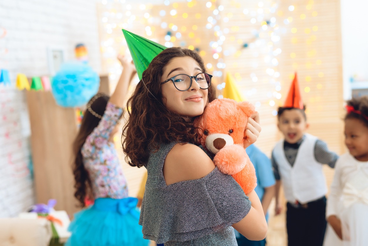 chica con gorrito de cumpleaños verde posa orgullosa con amigos de fondo desenfocados